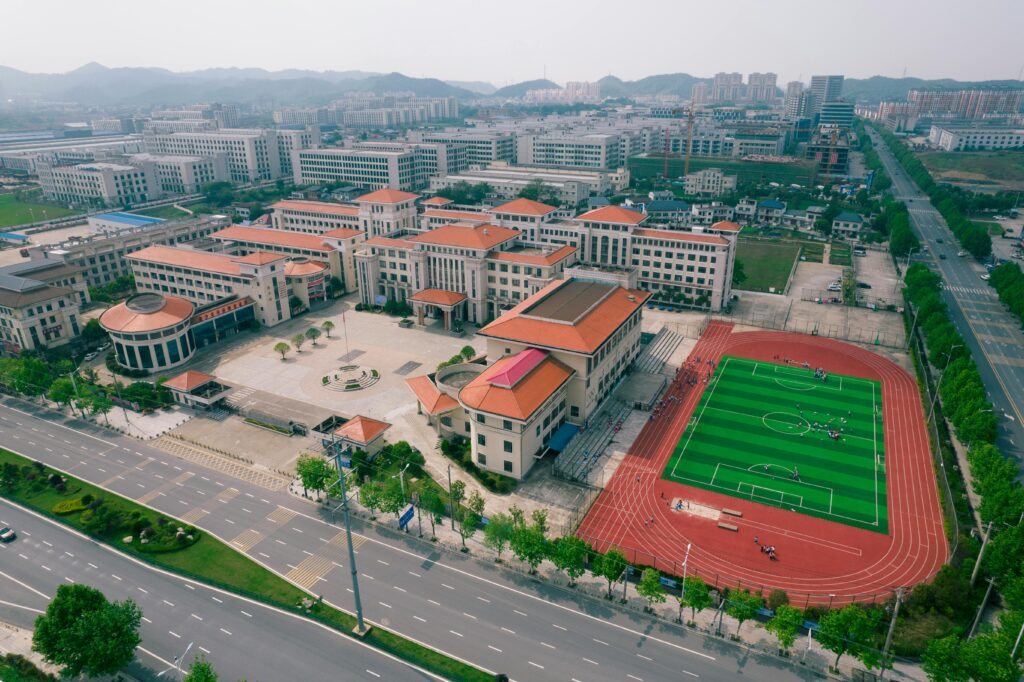 Aerial view of a modern school campus with sports field in Jiujiang, China.