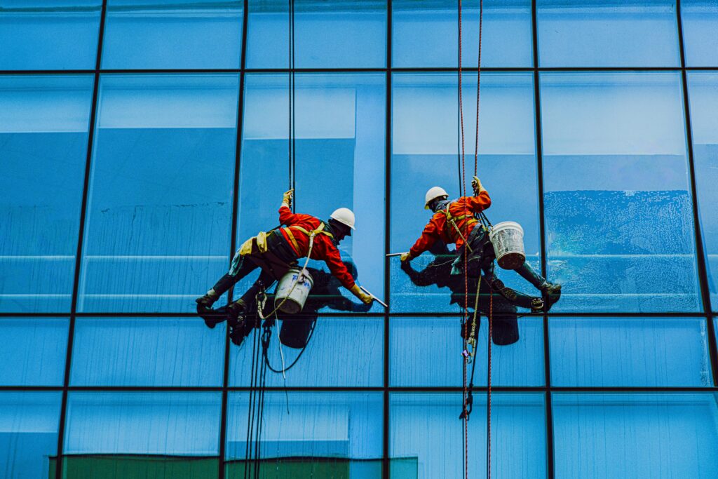 Window cleaners using safety harnesses on a skyscraper facade, captured in Vietnam.